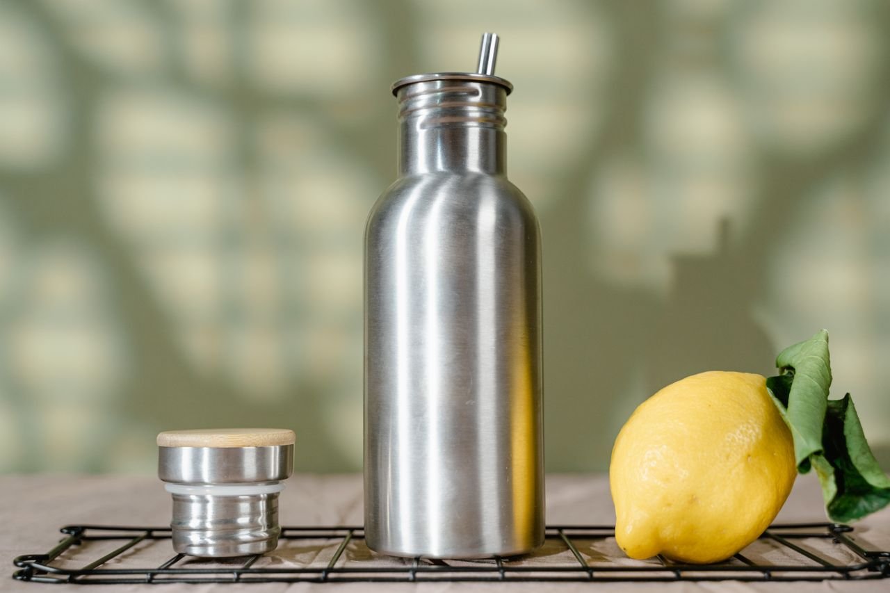 Eco-friendly stainless steel water bottle with a fresh lemon, promoting sustainability.